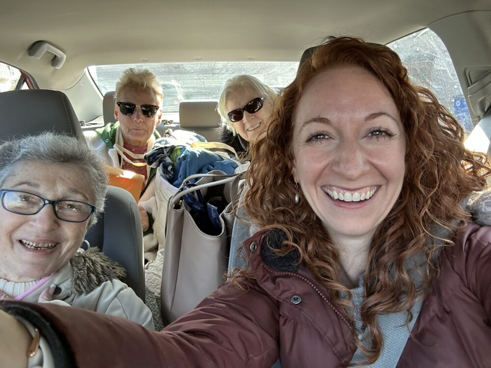 4 woman smiling riding in a car